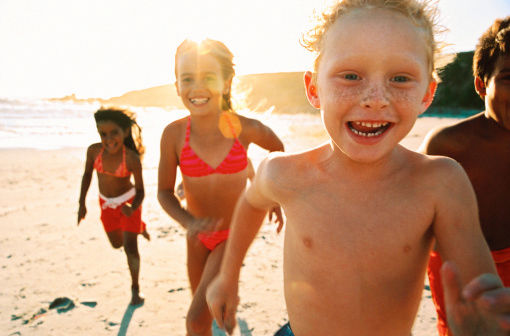 portrait of a group of children running on the beach